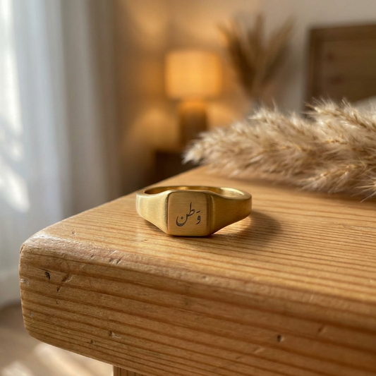 Gold ring with engraved text on a wooden surface with a blurred background
